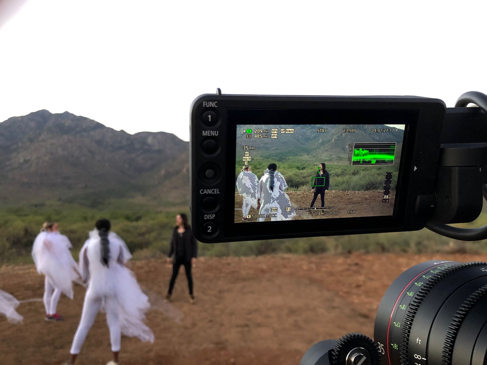 Molly Kate Kestner feat. Brock Monroe, "Get Up" — Director of Photography and camera operator. Behind the scenes out on location: a cinema camera in the foreground, its monitor carrying the picture, open ground and mountains beyond.