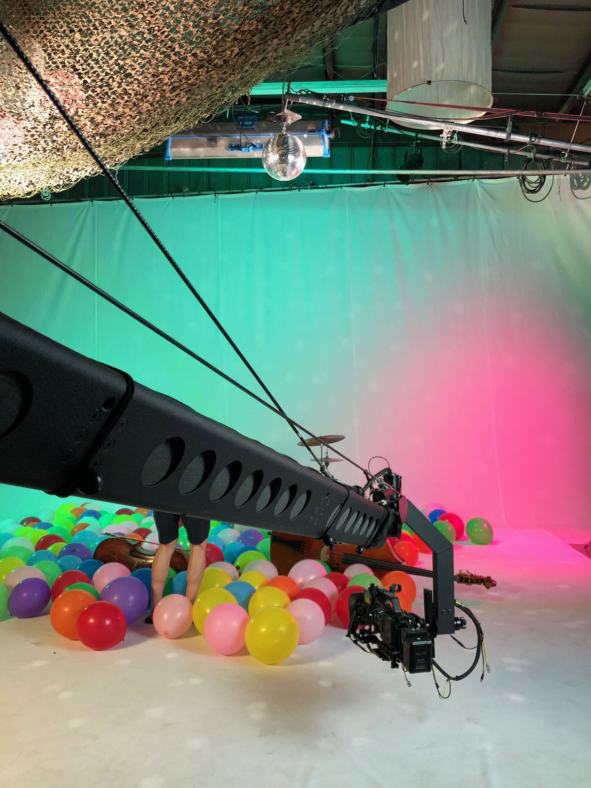Simply Three, "September" — Jib operator. Behind the scenes on the studio set: the camera rig under a draped ceiling of coloured light.