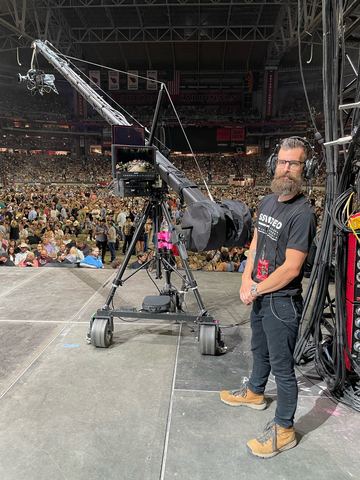 Jib — crane on a wheeled dolly at an arena floor.