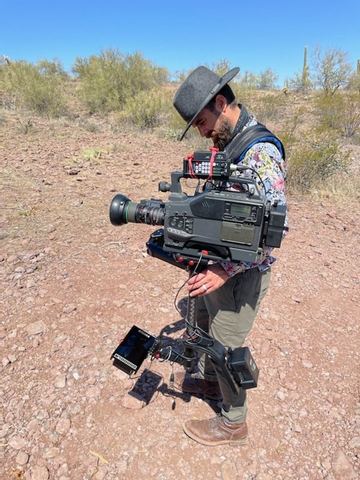 Steadicam — operator on a body-worn rig in desert scrub.