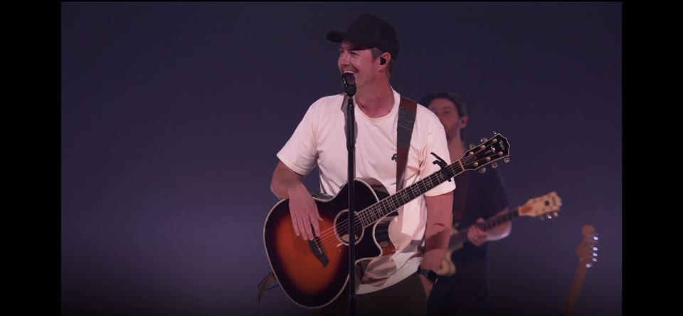 CCV Church live service (2024) — Jib. The worship leader on acoustic guitar, mid-song, with the band behind him.